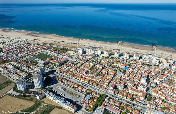 Praia da Cova do Vapor beach with fishing village and Tagus estuary near Lisbon